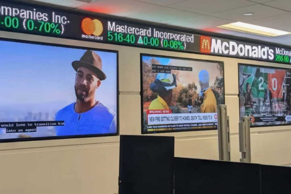 A Rise Display LED ticker, wall-mounted over several TVs in a classroom environment.
